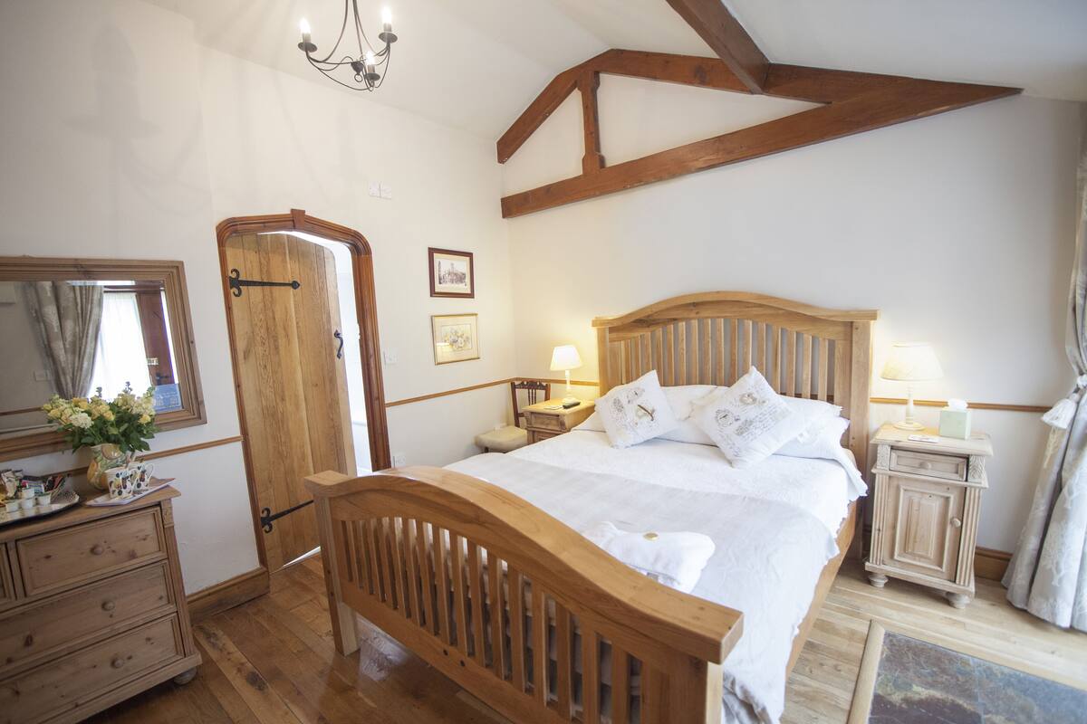 Une chambre à coucher avec un lit en bois, une commode, une table de chevet et un miroir.