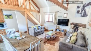 A cozy living room with a sofa, a coffee table, and a TV. There's a staircase leading to another level. - Beeches Farmhouse Country Cottages & Rooms (Bradford-on-Avon)