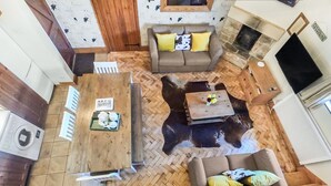 A cozy living area with a herringbone floor, a sofa with cushions, a coffee table, and a fireplace. - Beeches Farmhouse Country Cottages & Rooms (Bradford-on-Avon)