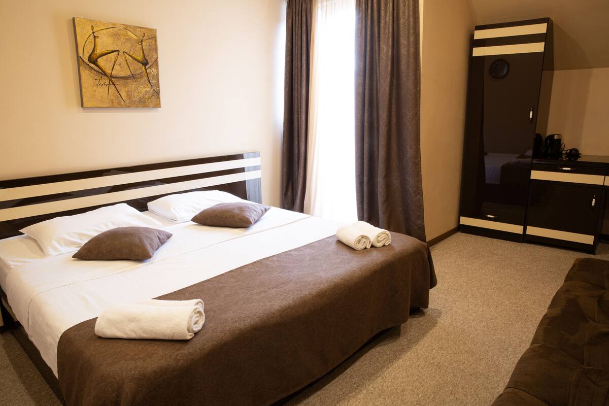 Ein Hotelzimmer mit einem großen Bett, einem Schminktisch, einem Spiegel und einem Bild an der Wand.