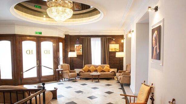 A lobby with a checkered floor, a chandelier, and a sofa with yellow cushions. - Hotel Diplomat (Tbilisi)
