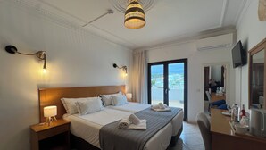 A hotel room with a large bed, bedside lamps, a desk with a chair, a television, and a view through the door. - ETHOS Bertolina Wellness Urban Living. (Albufeira)