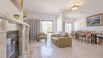 A spacious living room with a fireplace, a sofa, and a dining area with wooden chairs and a table.