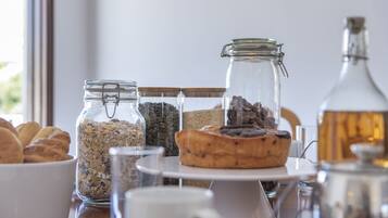 Ett frukostbord med olika sorters mat, inklusive bakverk, en muffin och burkar med müsli och frön.