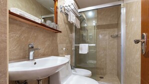 Un baño con lavabo, inodoro y ducha con cerramiento de vidrio.