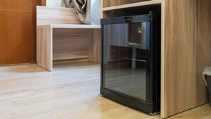 Una kitchenette compacta con refrigerador empotrado, muebles de madera y una banca.