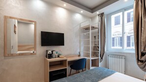 Una habitación de hotel moderna con una cama, un escritorio con una silla, un televisor, un armario y una ventana con cortinas.