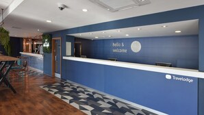 Een receptiegedeelte met een blauwe muur, een klok en een bord met de tekst 'hello & welcome'.