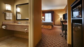 Een hotelkamer met een badkamer, een bed, een bureau en een televisie.
