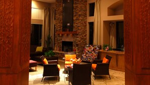 A spacious living area with a stone fireplace, comfortable seating, and a stone-tiled floor. - Raintree at Phoenix South Mountain Preserve (Phoenix)