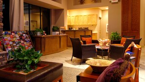 A lobby with a reception desk, wicker furniture, a coffee machine, and a welcome sign. - Raintree at Phoenix South Mountain Preserve (Phoenix)