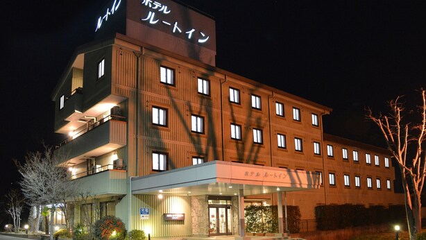 A hotel with multiple floors, a prominent sign at the top, and a well-lit entrance. - Hotel Route-Inn Court Minami Alps (Minami-Alps)