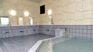 A spa area with a stone wall, multiple sinks, and a hot tub. - Hotel Route-Inn Court Minami Alps (Minami-Alps)