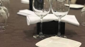 Una mesa con copas de vino y un plato blanco, con una caja negra y una servilleta blanca sobre la mesa.