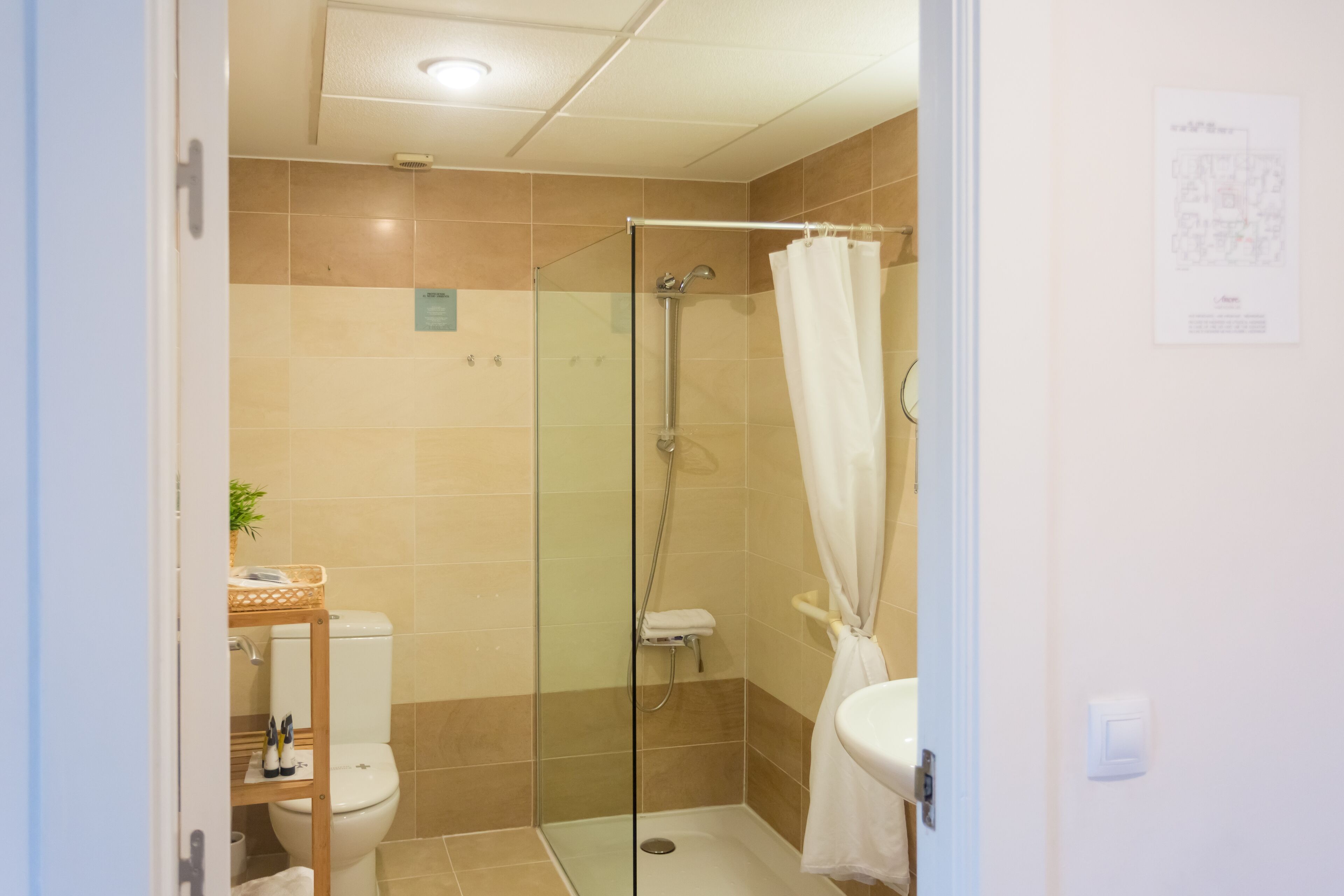 Un baño con cabina de ducha de vidrio, inodoro y lavabo.