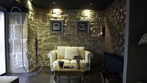 A cozy room with a stone wall, a cream-colored sofa, a wooden coffee table, and a wicker chair. - Hotel Arrope (Haro)