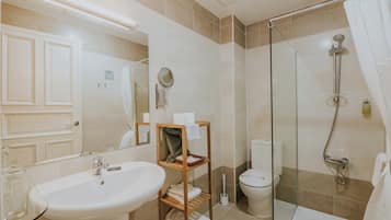 A modern bathroom with a sink, mirror, toilet, and glass-enclosed shower.