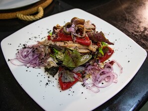 A white plate with a salad containing various vegetables and meat. - Hotel Arrope (Haro)