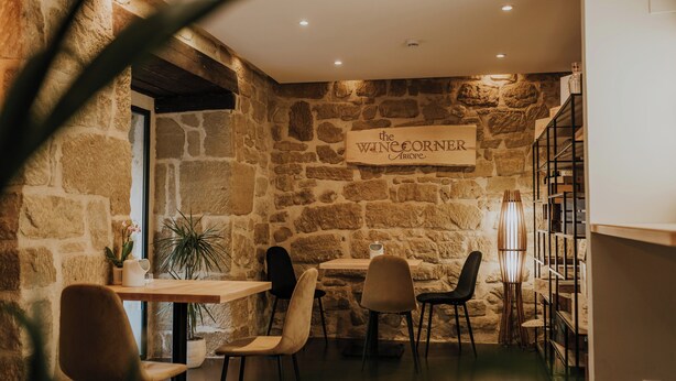 A cozy restaurant interior with stone walls, wooden tables, and chairs. A sign reads "The Wine Corner." - Hotel Arrope (Haro)