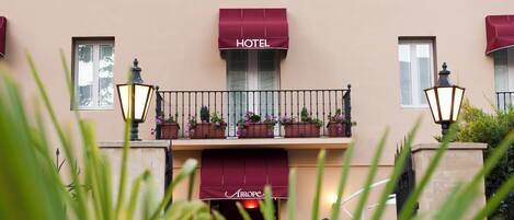 Fachada de hotel con balcón, toldo rojo y un letrero que dice "HOTEL".