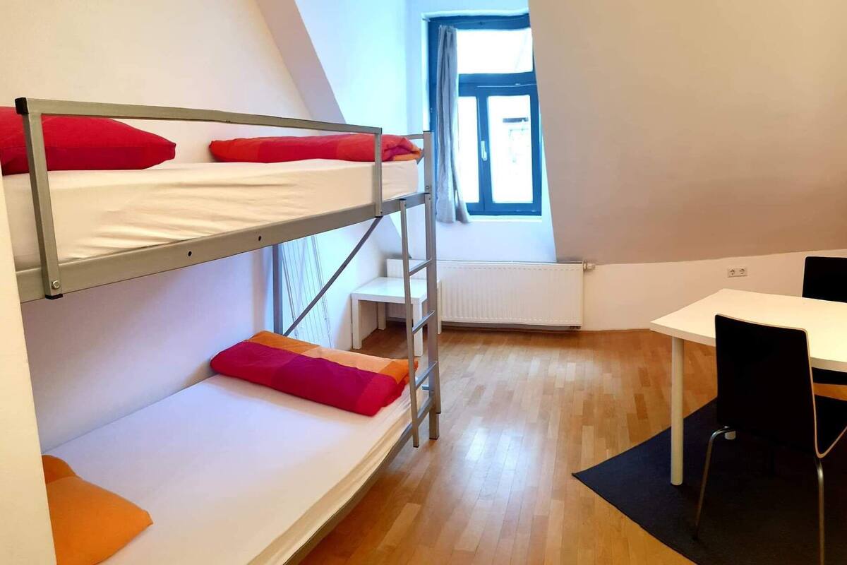 Quarto tipo dormitório com beliches, escrivaninha e janela.