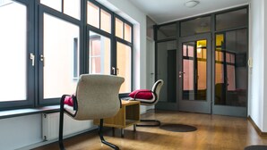 A modern room with large windows, a wooden floor, and two chairs. - Cukrarna Hostel (Kranj)