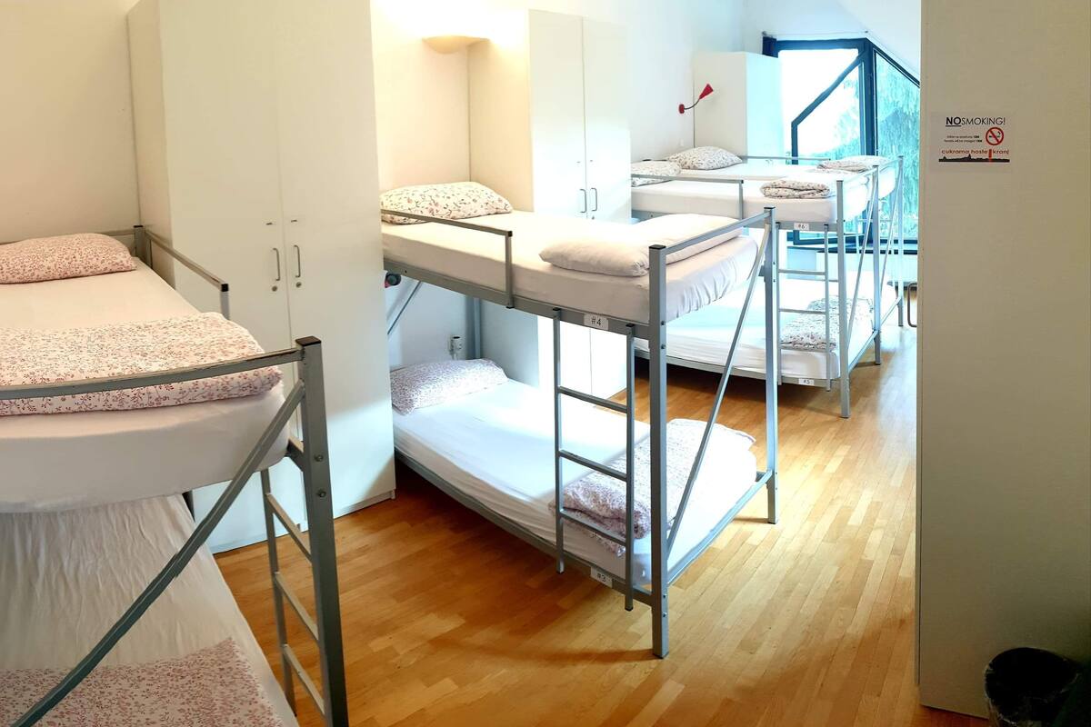 Um quarto de dormitório com beliches, um guarda-roupa e um aviso de 'Não Fumar'.