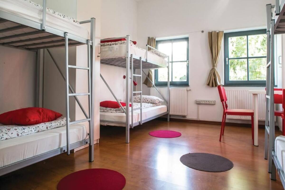 Um quarto de dormitório com beliches, uma escrivaninha e uma cadeira.