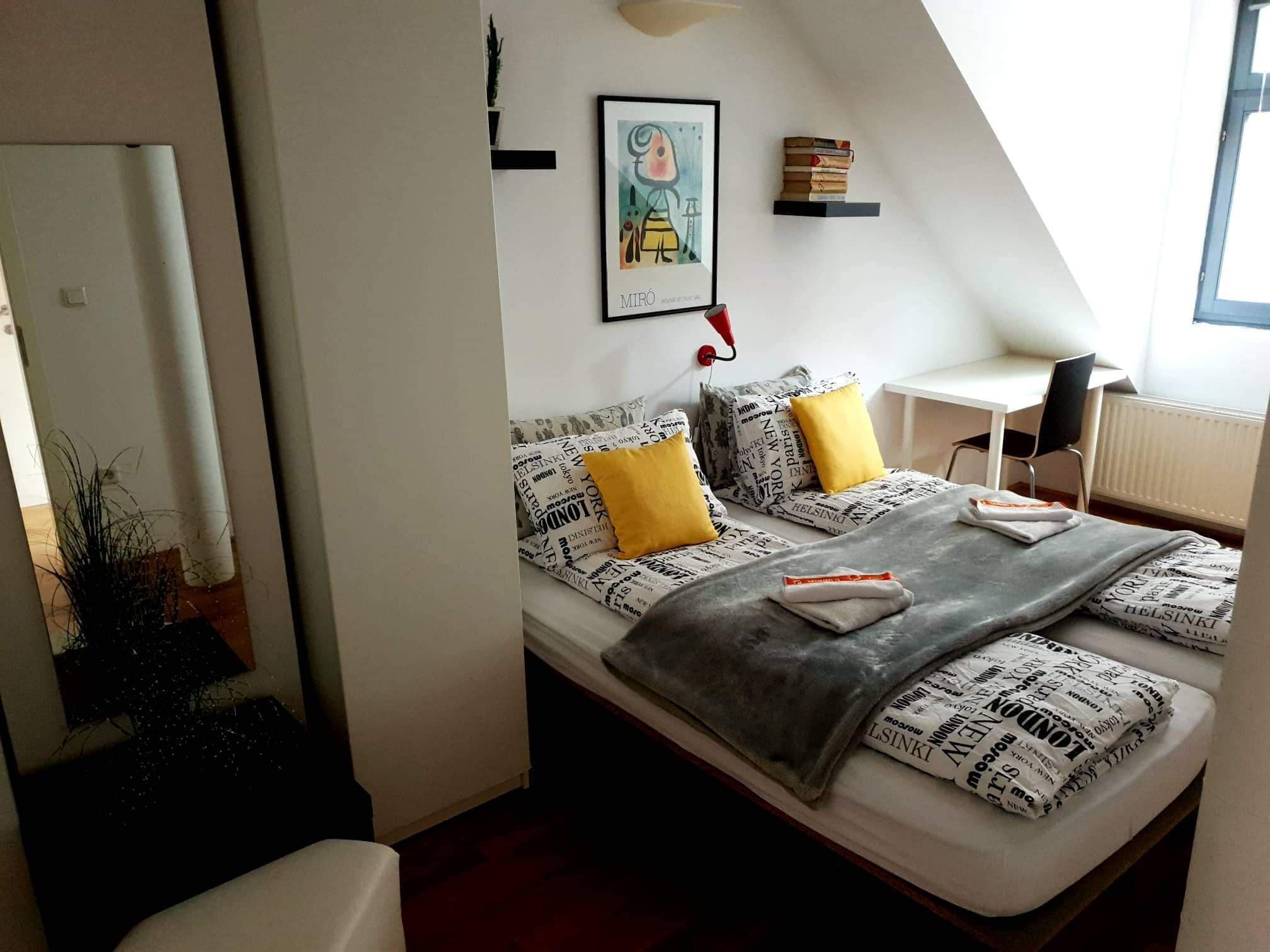 Un dormitorio moderno con una cama con ropa de cama estampada, un escritorio y una obra de arte enmarcada en la pared.