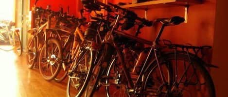 Bicycles parked in a row against a wall in a room with wooden flooring.