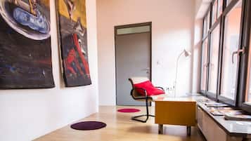 A modern interior with a wooden floor, a red chair, a small wooden table, and a bookshelf with books.