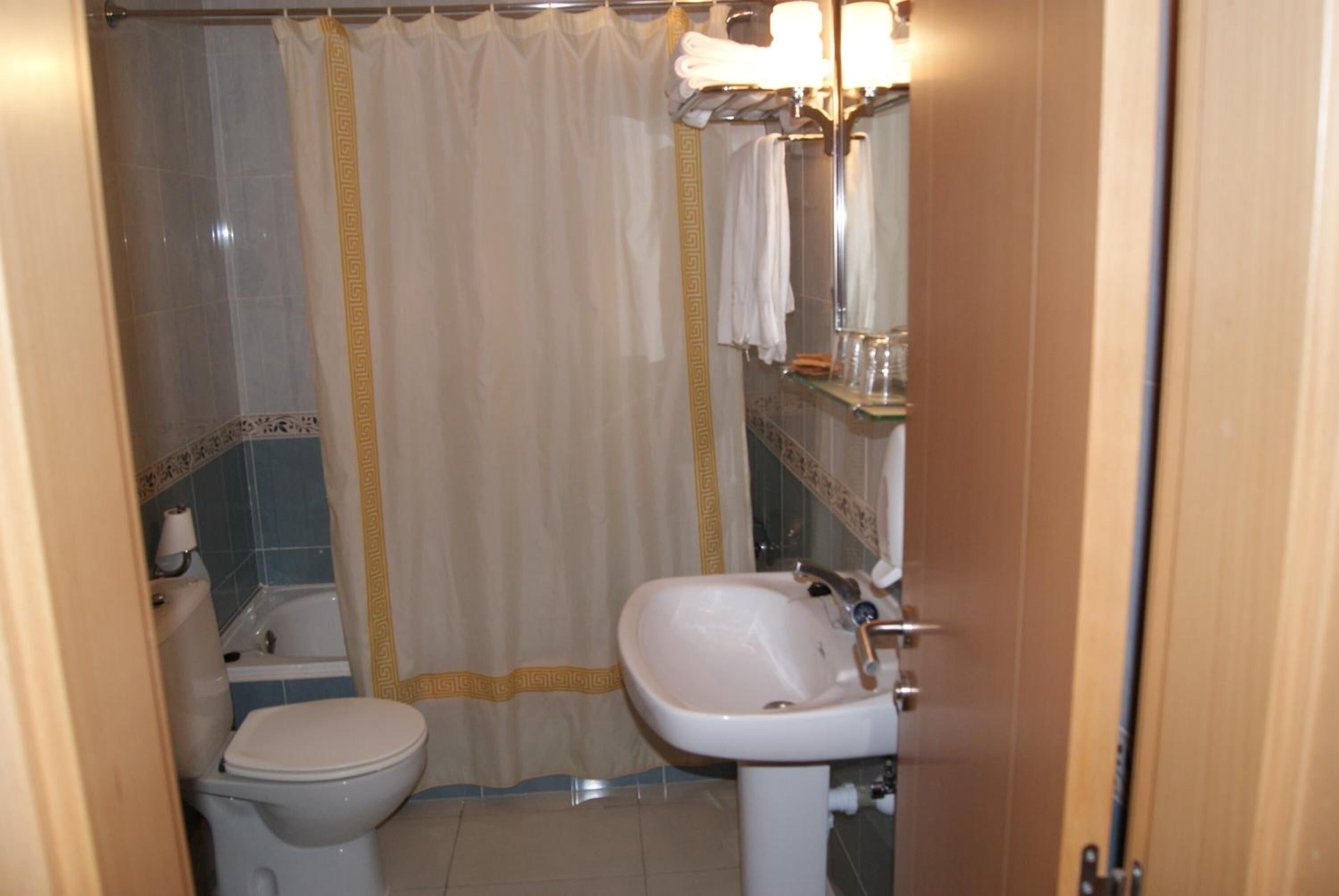 Een badkamer met toilet, wastafel en douchegordijn.
