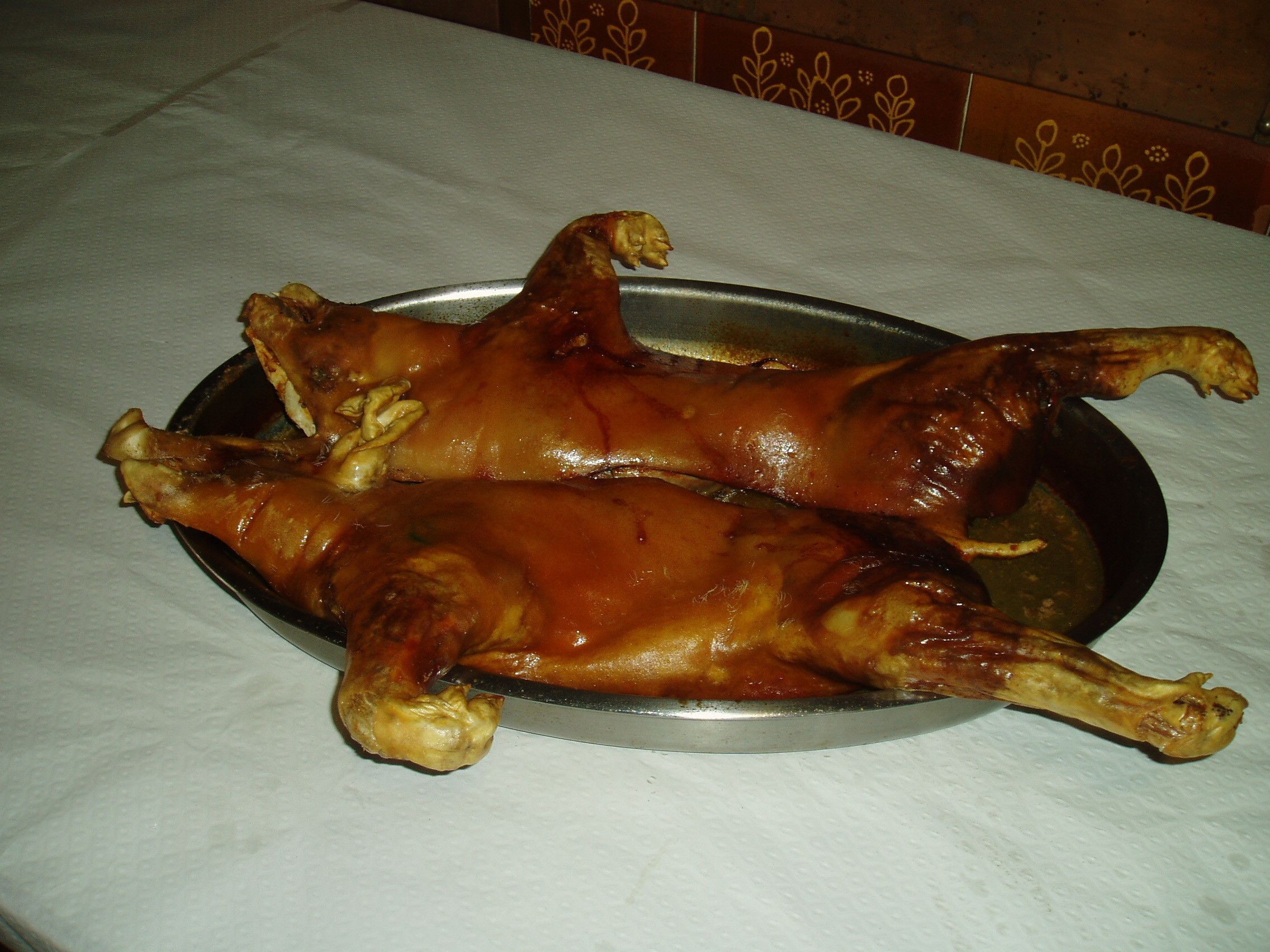 Two roasted chickens on a metal tray.