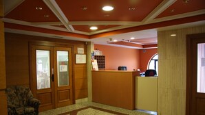 A reception area with a wooden desk, a chair, and a bulletin board. - Hotel Alameda (Alba de Tormes)