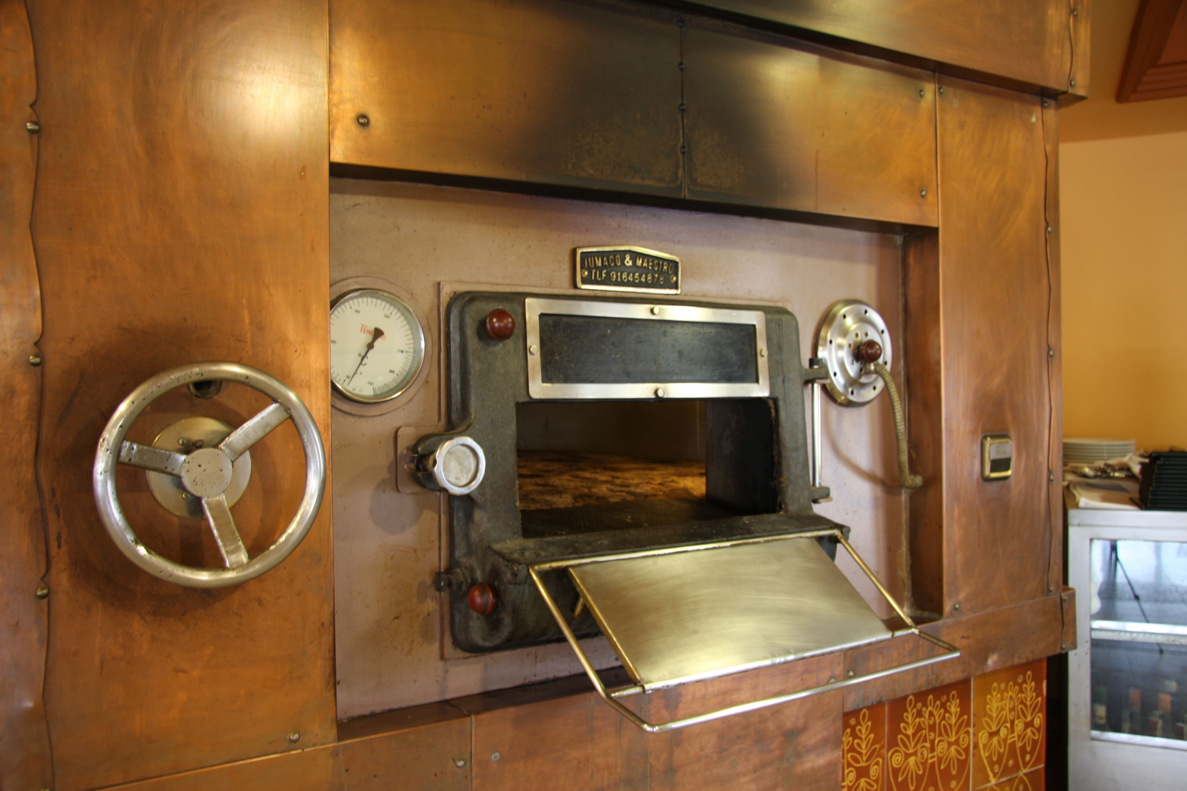 A vintage oven with a control panel, a thermometer, and a metal door.