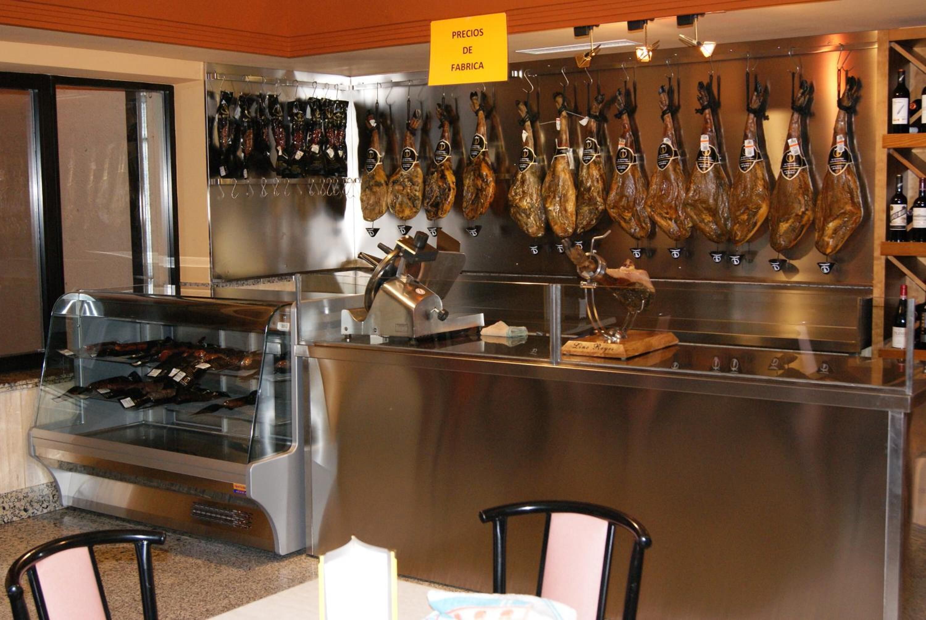 Eine Fleischtheke mit aufgehängten Schinken und einer Kühlvitrine mit verpacktem Fleisch.