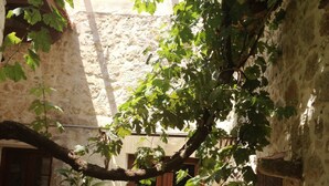 Un patio con un rústico muro de piedra, una puerta de madera y una pequeña mesa.