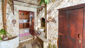 A rustic stone kitchen with wooden cabinets, a sink, and a hanging bicycle.