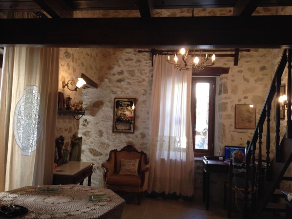 A cozy room with a stone wall, a chandelier, a wooden staircase, and a table with a lace tablecloth. - Traditional Cretan Houses (Heraklion)