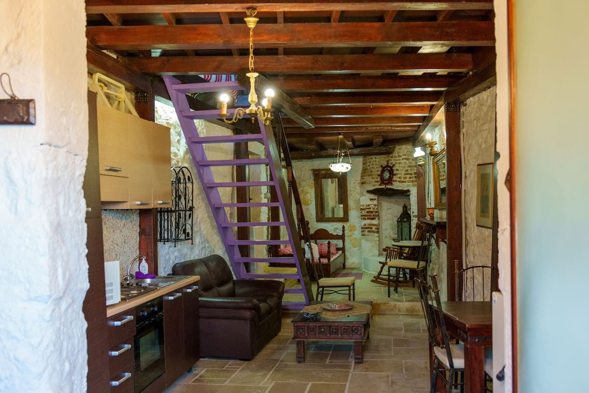 Ein rustikales Interieur mit Küche, Essbereich und einer Treppe, die zu einer oberen Ebene führt.