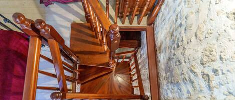 A wooden spiral staircase with a handrail, leading to an upper floor.