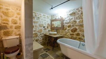 A bathroom with a stone wall, a toilet, a sink, and a bathtub.