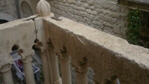 A stone wall with a window and a balcony railing. - Palace Stafileo (Trogir)