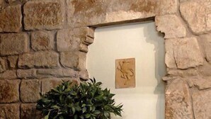 A stone wall with a wooden planter holding a potted plant and a small topiary. - Torre di Vico Residenza d'Epoca (Viterbo)