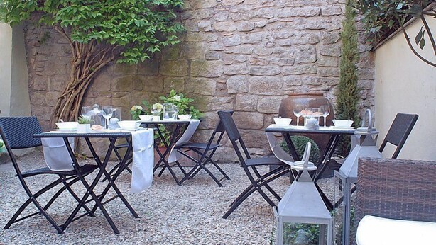 An outdoor patio with stone walls, tables, and chairs, some with umbrellas. - Torre di Vico Residenza d'Epoca (Viterbo)