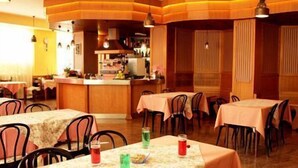 A restaurant with multiple tables and chairs, a bar area, and wooden paneling on the walls. - Hotel Ducale (Salsomaggiore Terme)