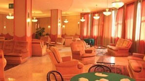 A hotel lobby with multiple seating areas, including sofas and armchairs, arranged around a central coffee table. - Hotel Ducale (Salsomaggiore Terme)