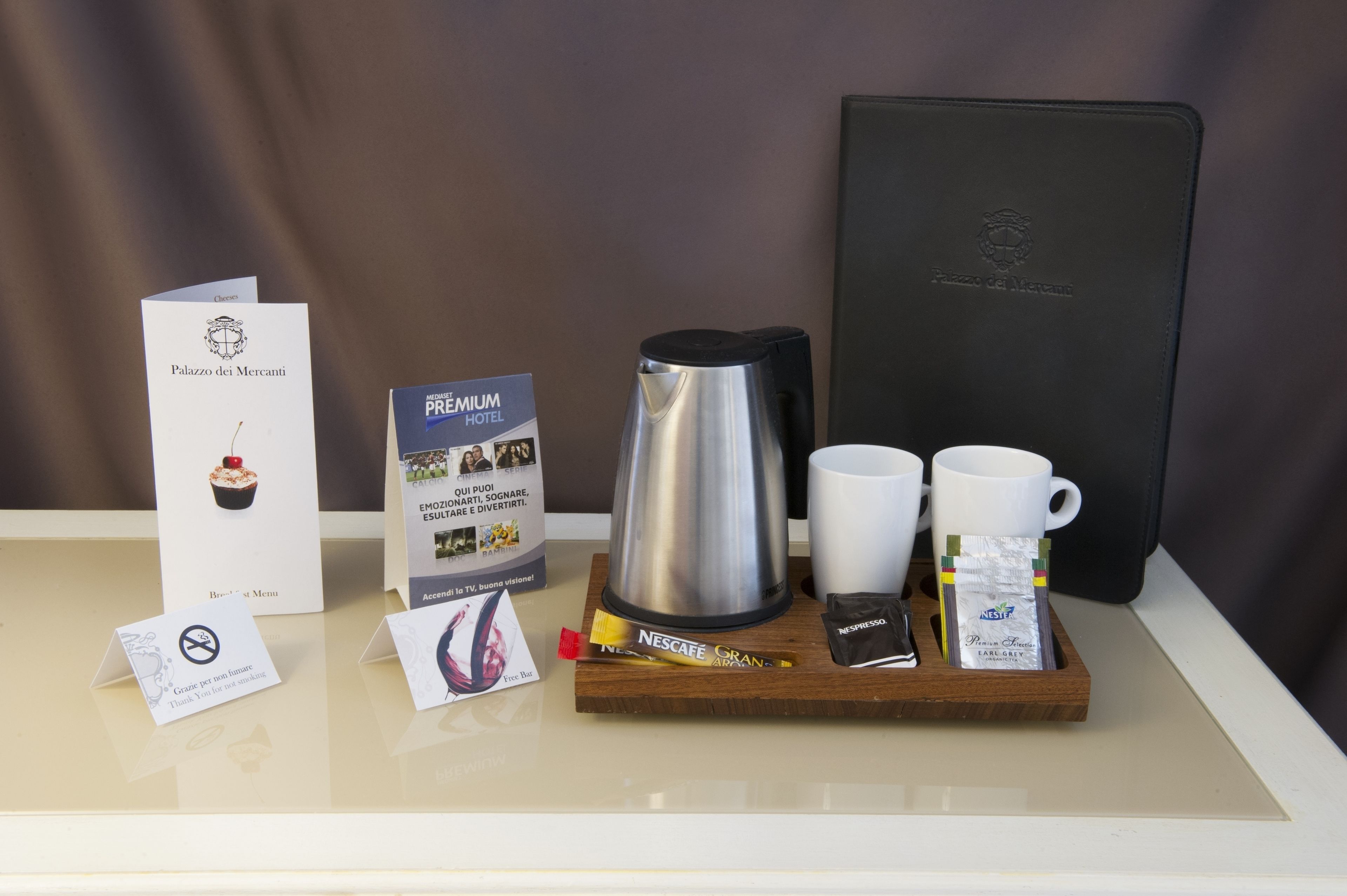 Ontbijt in een hotelkamer, met een koffiezetapparaat, twee kopjes en een dienblad met koffieporties en een menukaart.