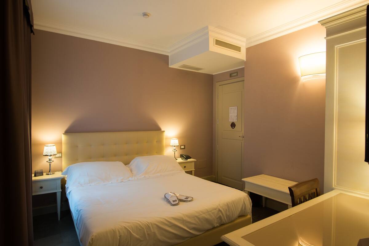 Une chambre d’hôtel avec un lit, des tables de chevet, un bureau et une chaise.
