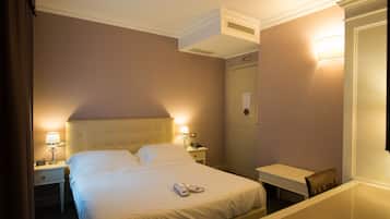 A hotel room with a bed, bedside tables, a desk, and a chair.